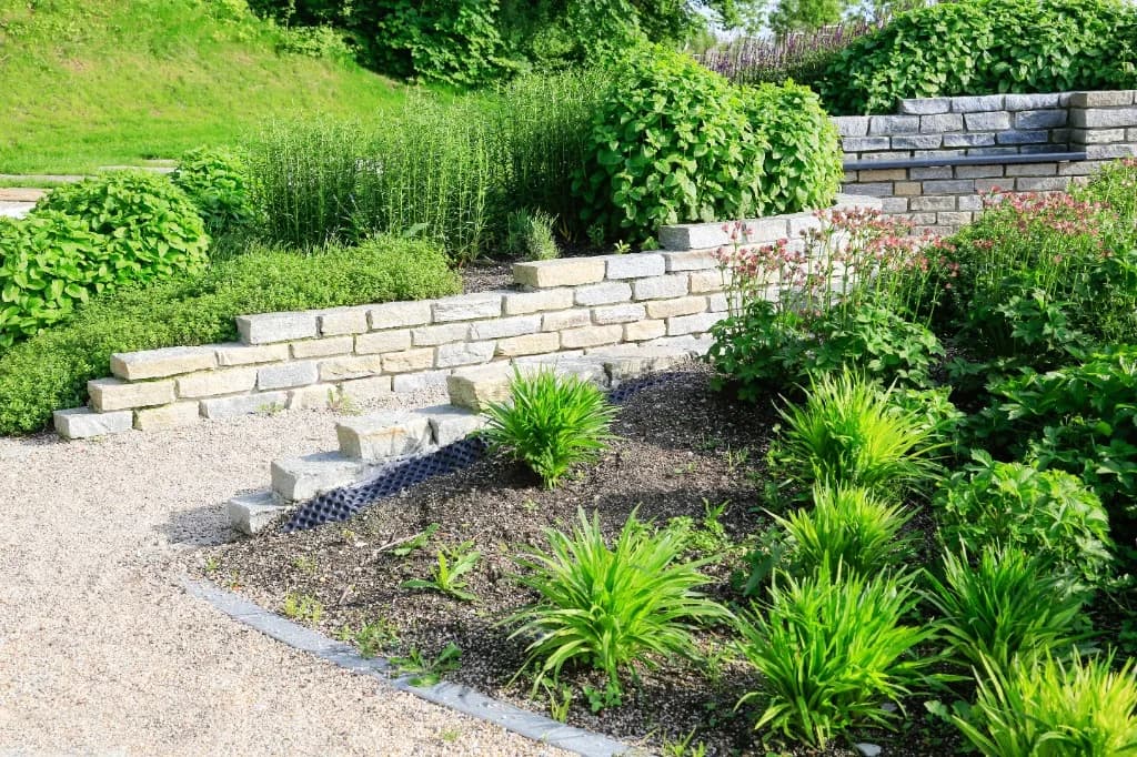 Terrassierter Garten mit Natursteinmauern und Bepflanzung