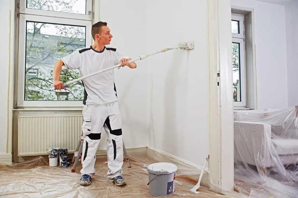 Maler bei sauberen Malerarbeiten an einer Innenwand